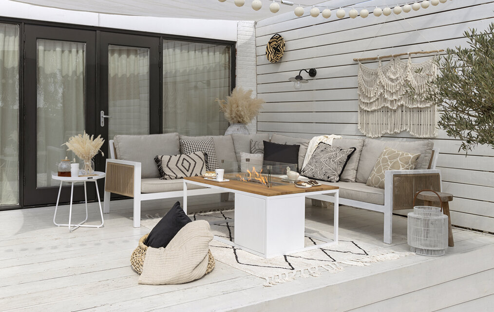 Ibiza Terrasse mit hellem Ecklounge-Set aus aluminium mit zwei Holz Beistelltischen und einem beigen Outdoor-Teppich