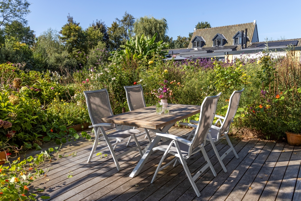Weißes Gartenmöbel-Set aus Aluminium auf Holzdielen in einem Landhausgarten